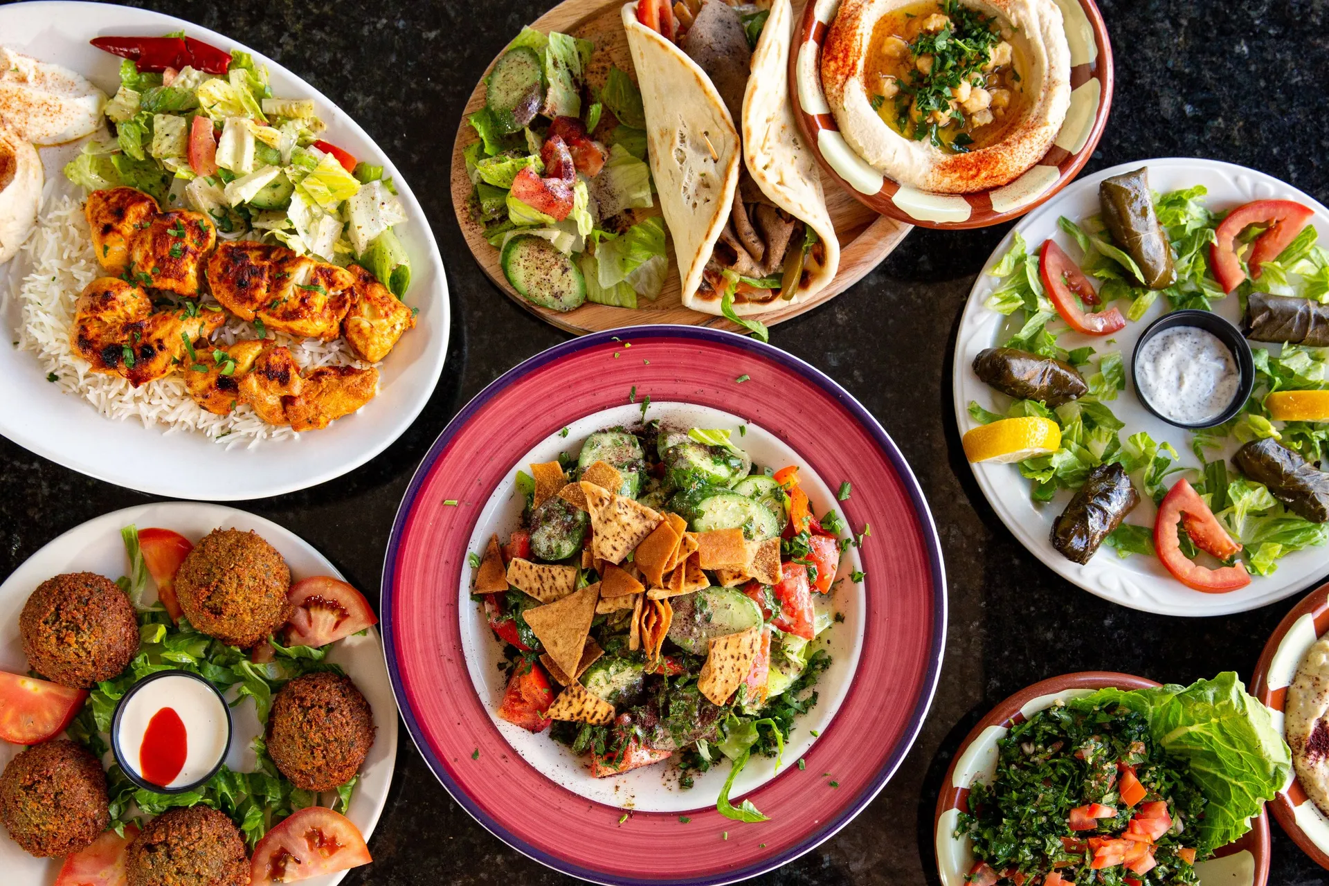 Overhead spread of chicken tawook, gyros, hummus, falafel and Lebanese salads